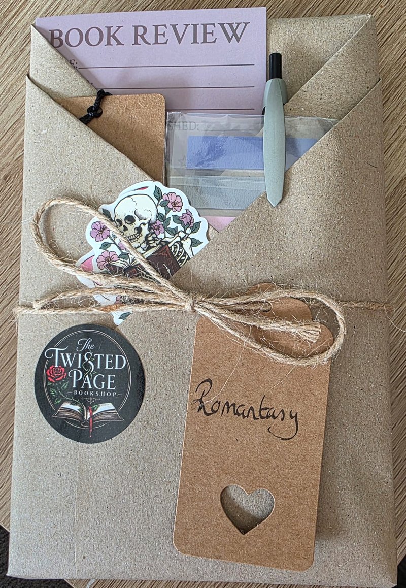 Blind Date with a Book, Romantasy pick — a kraft-paper wrapped parcel tied with twine, with a heart-cutout "Romantasy" gift tag